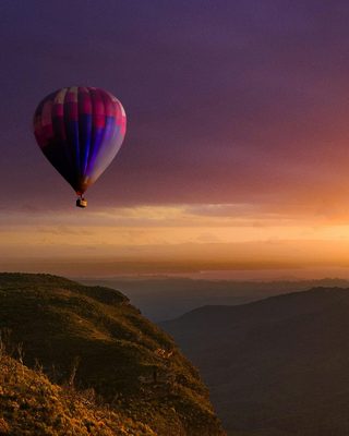 A hot air balloon over the mountains at sunset