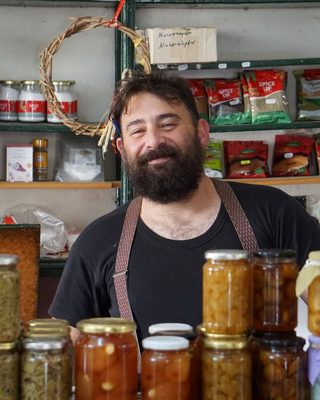 A smiling shop owner among jars in his store
