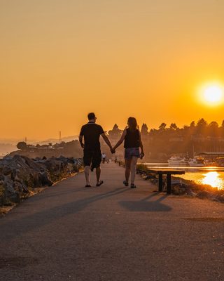 A couple walking hand in hand at sunset